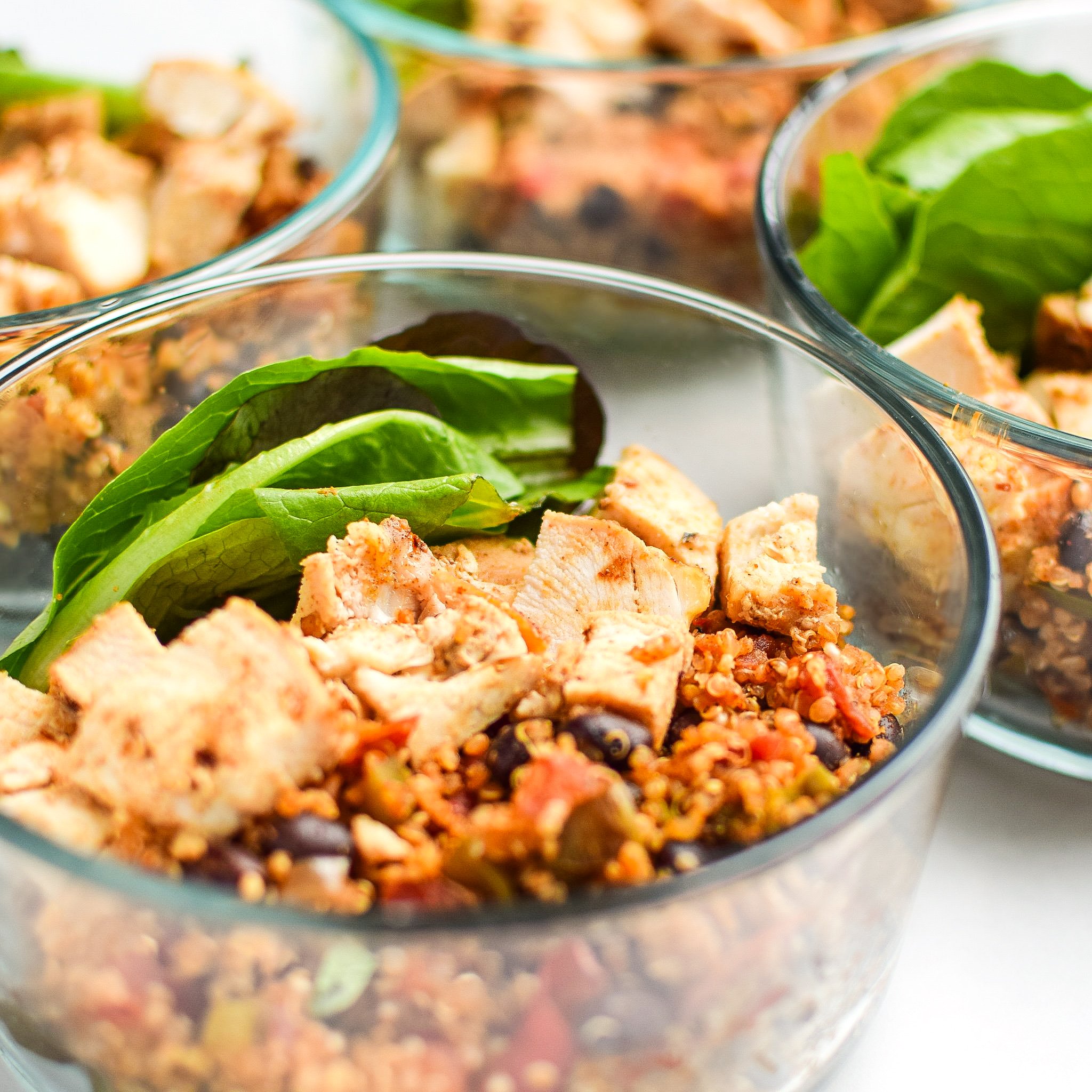 Meal prep lunch with mexican quinoa, chicken breast and hearty green leaves in Pyrex. 