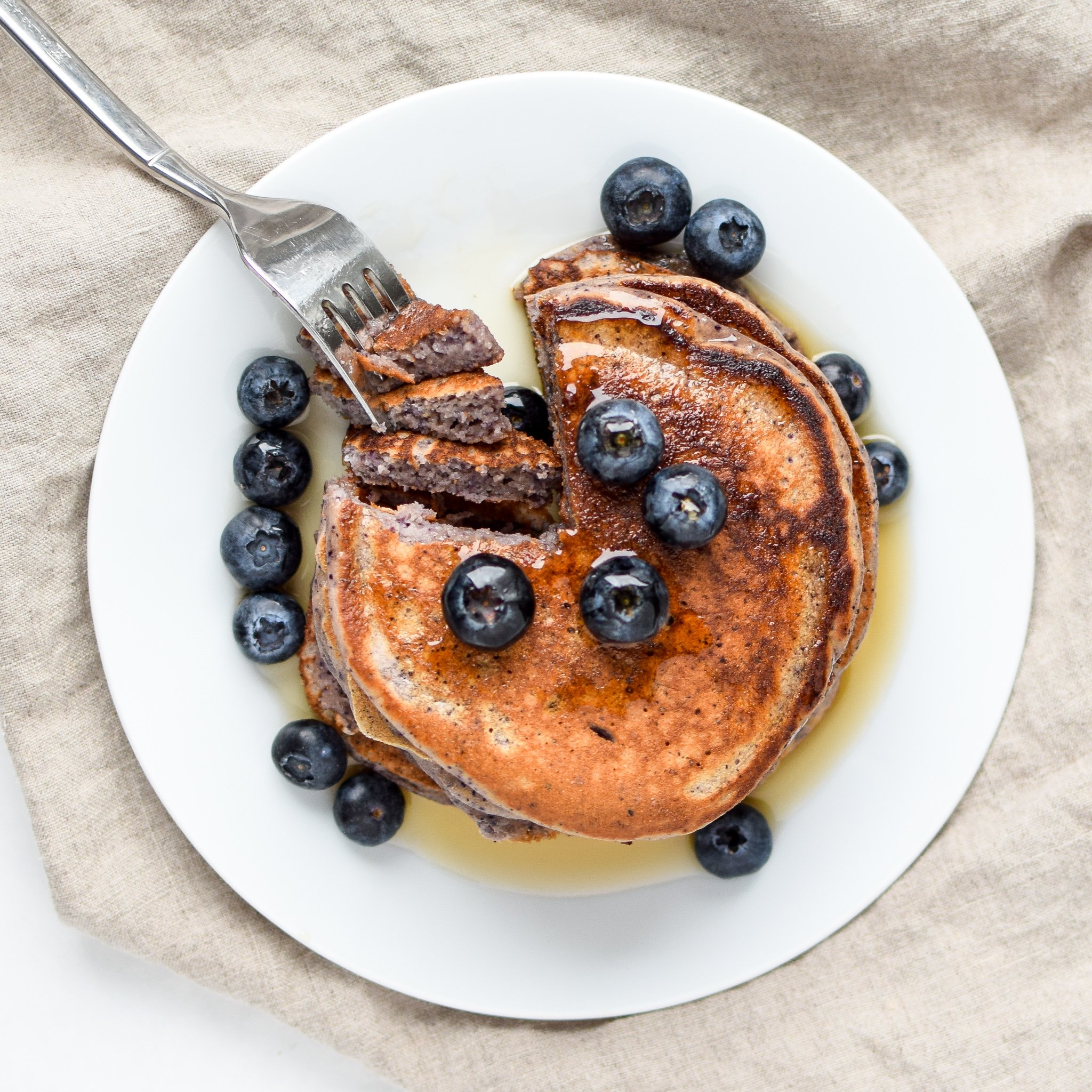 Lemon Poppy Seed Blueberry Protein Pancakes topped with blueberries and maple syrup
