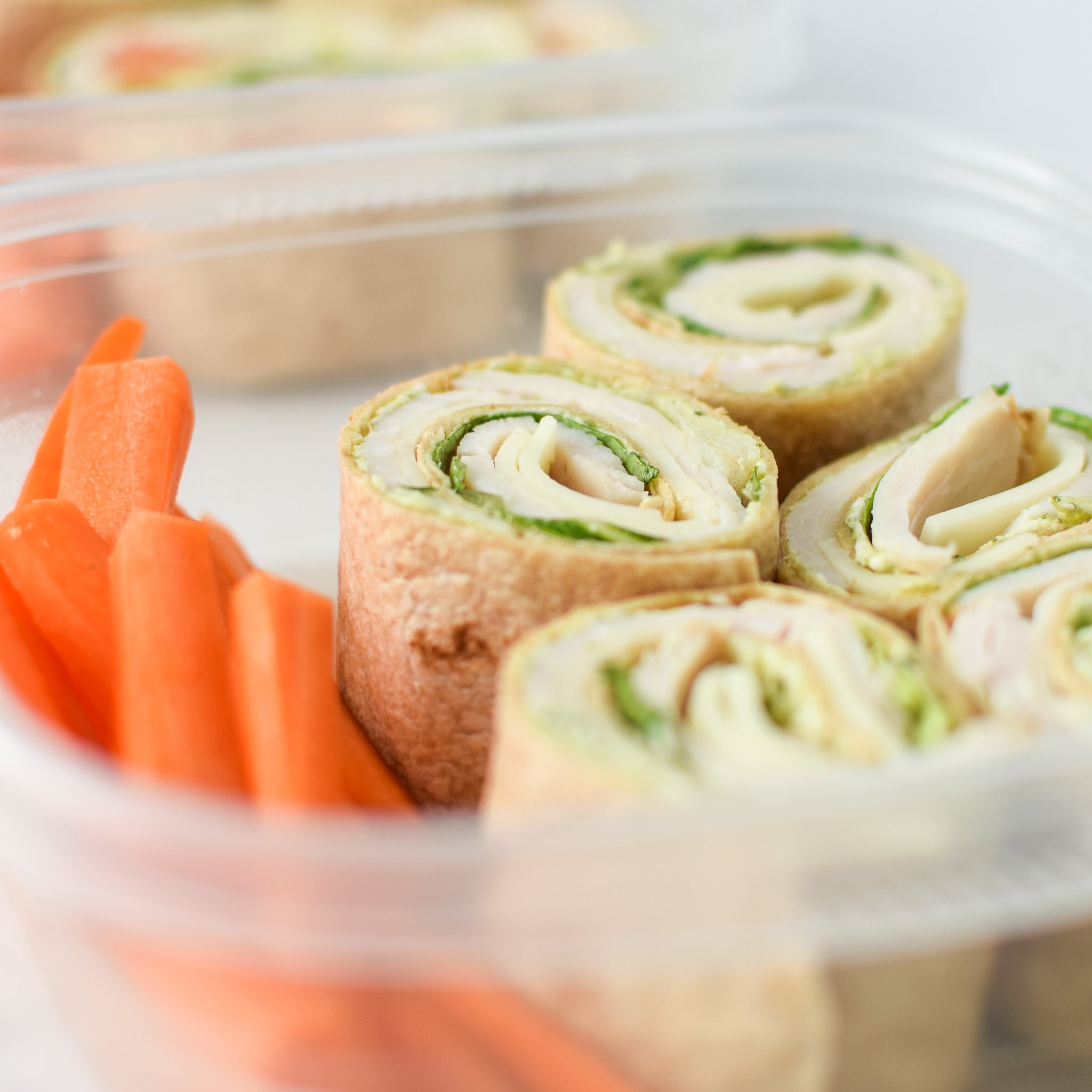 Turkey Pesto Tortilla Pinwheels meal prepped with carrot sticks