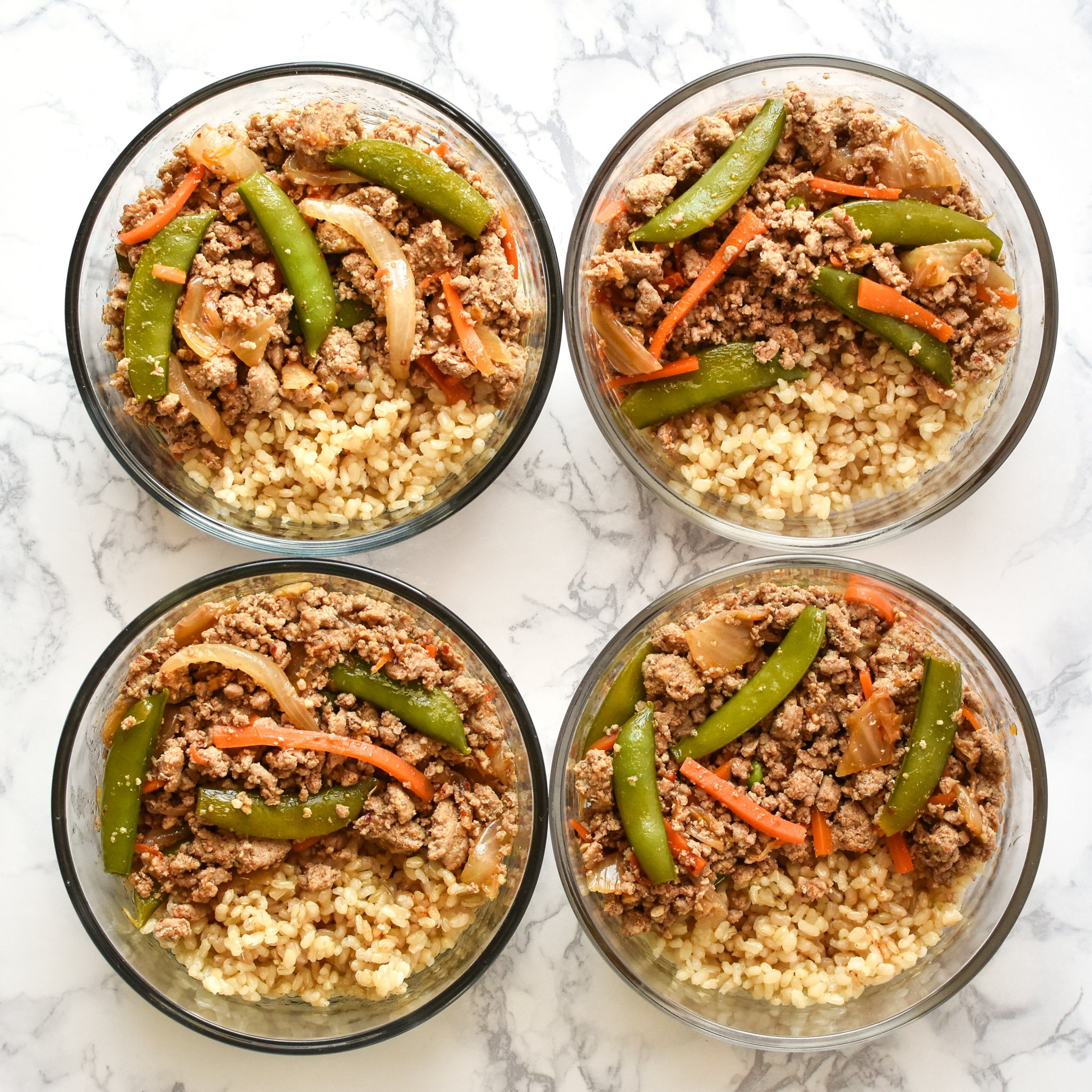 Ground turkey snap pea rice bowl meal prep in round pyrex meal prep containers.
