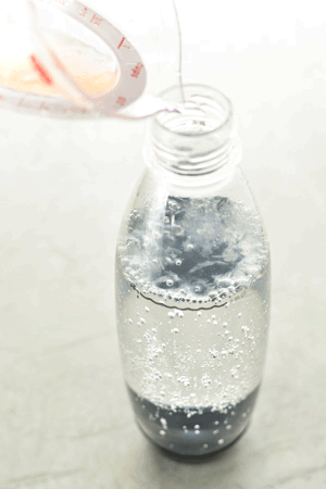 A GIF of grapefruit juice being poured into a SodaStream carbonating bottle.