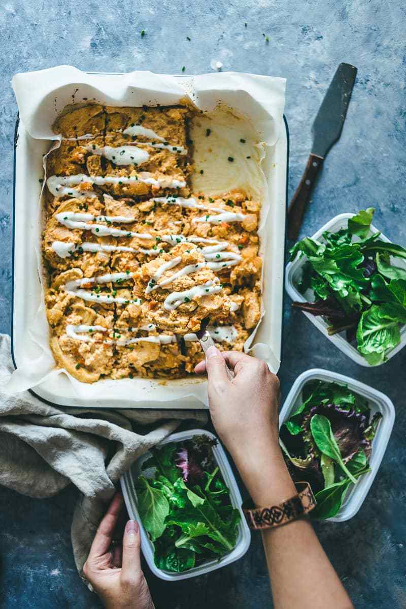 Buffalo chicken chicken being meal prepped with fresh greens. 