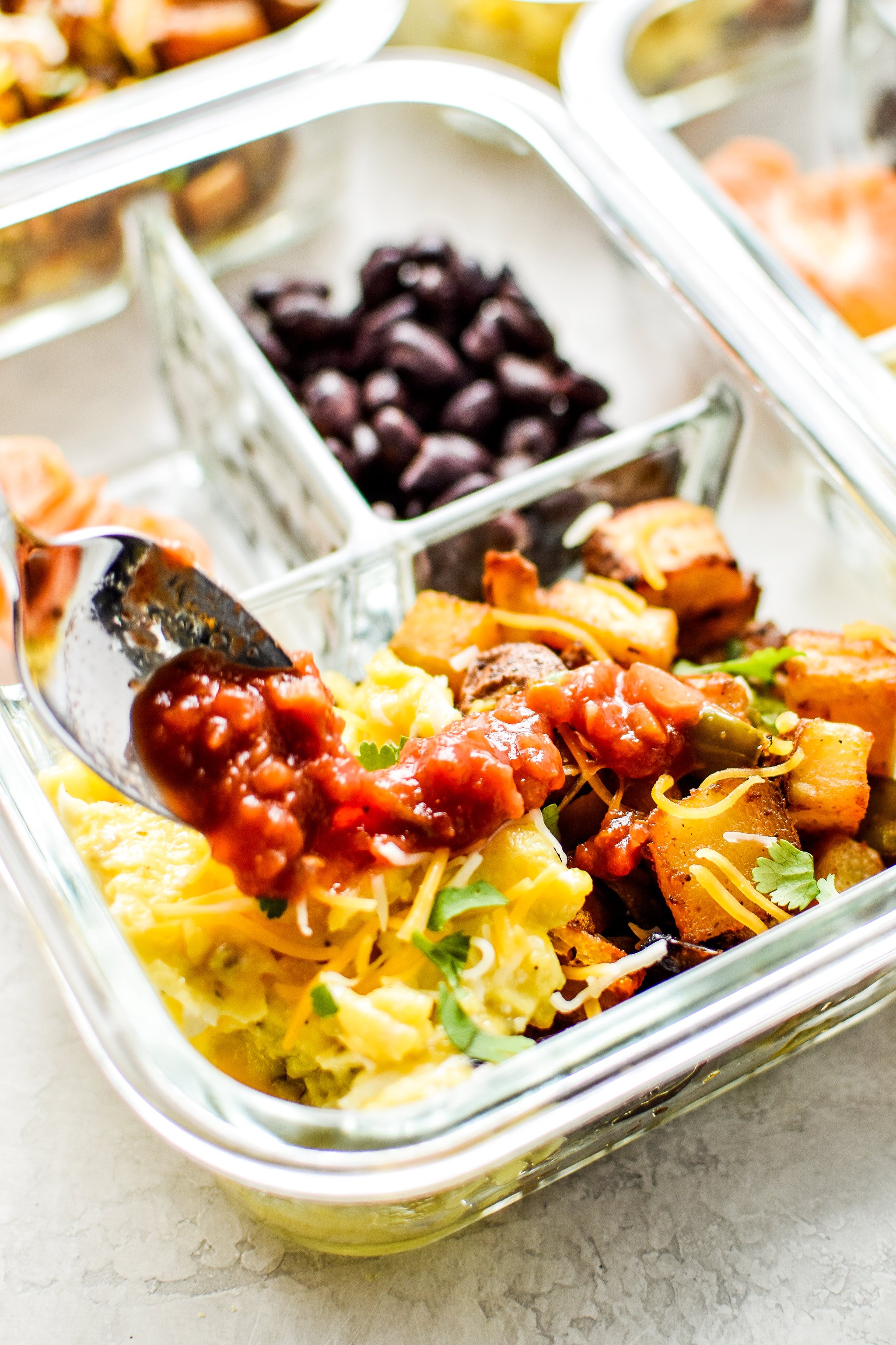 Using a spoon to place salsa on the breakfast potatoes and eggs. 