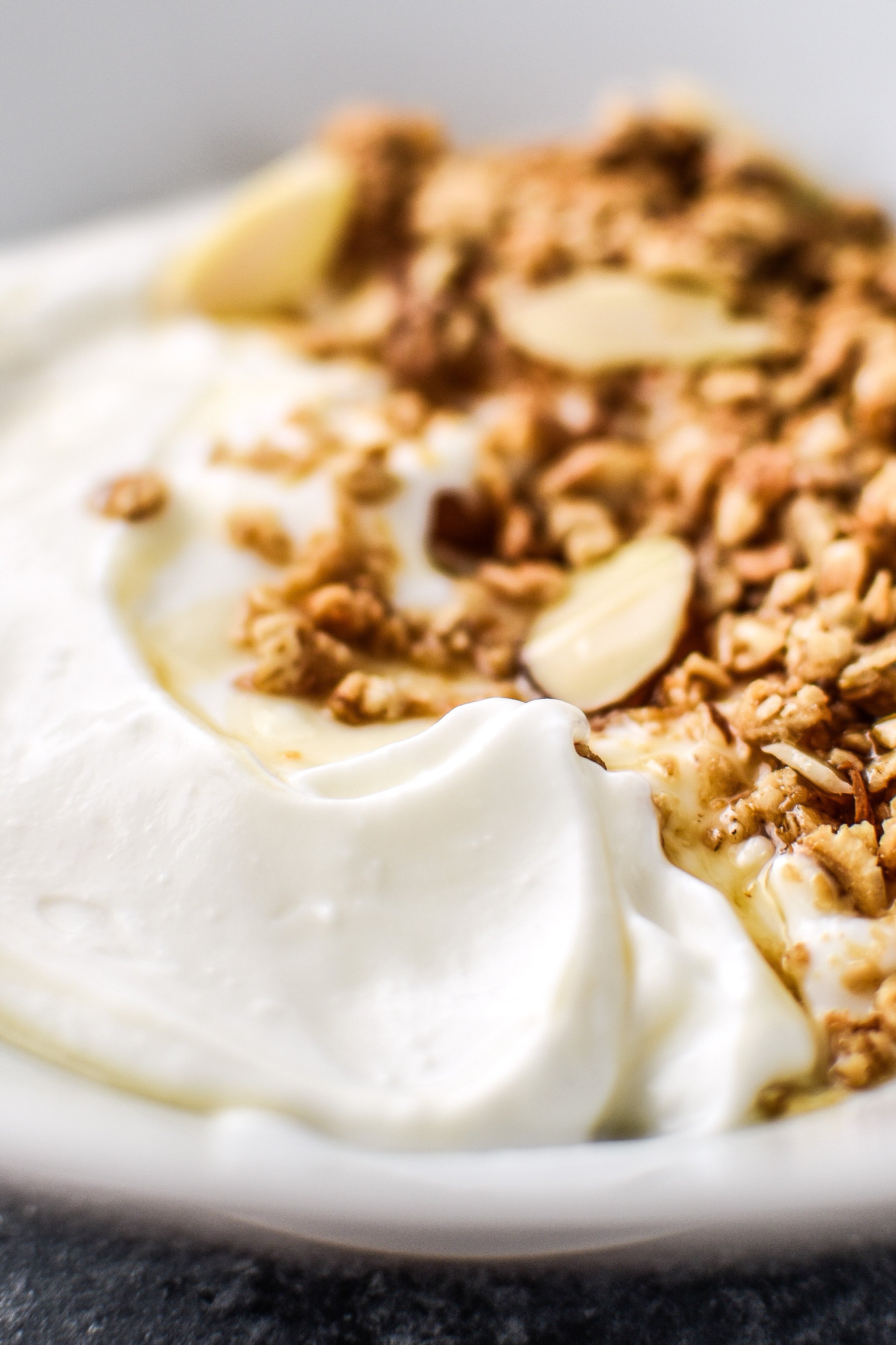 Freshly made yogurt in a bowl with granola and thin maple drizzle.