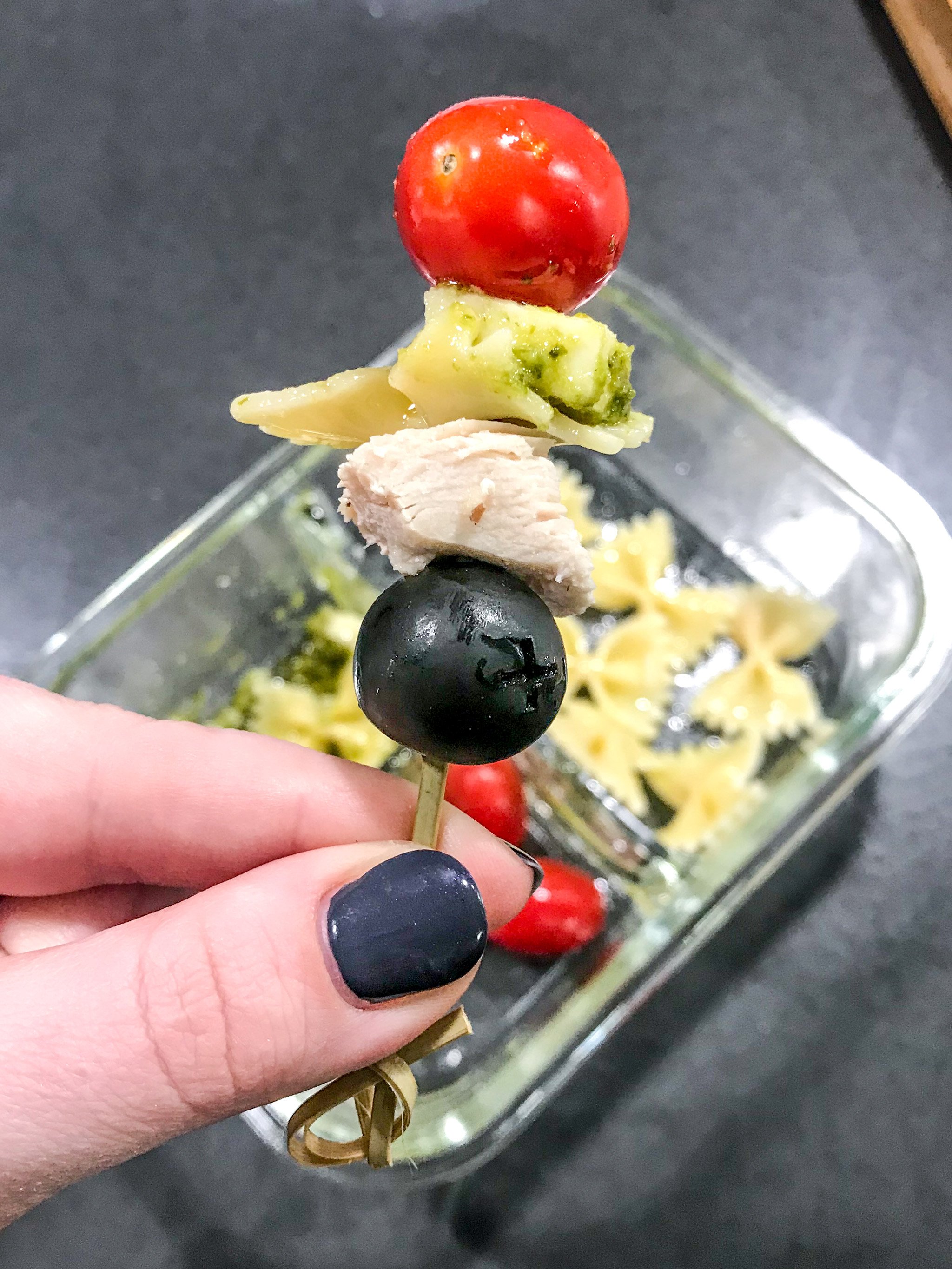 A skewer made of black olive, chicken breast, pesto pasta, fresh mozzarella and grape tomates from the DIY Chicken pesto pasta skewers meal prep.