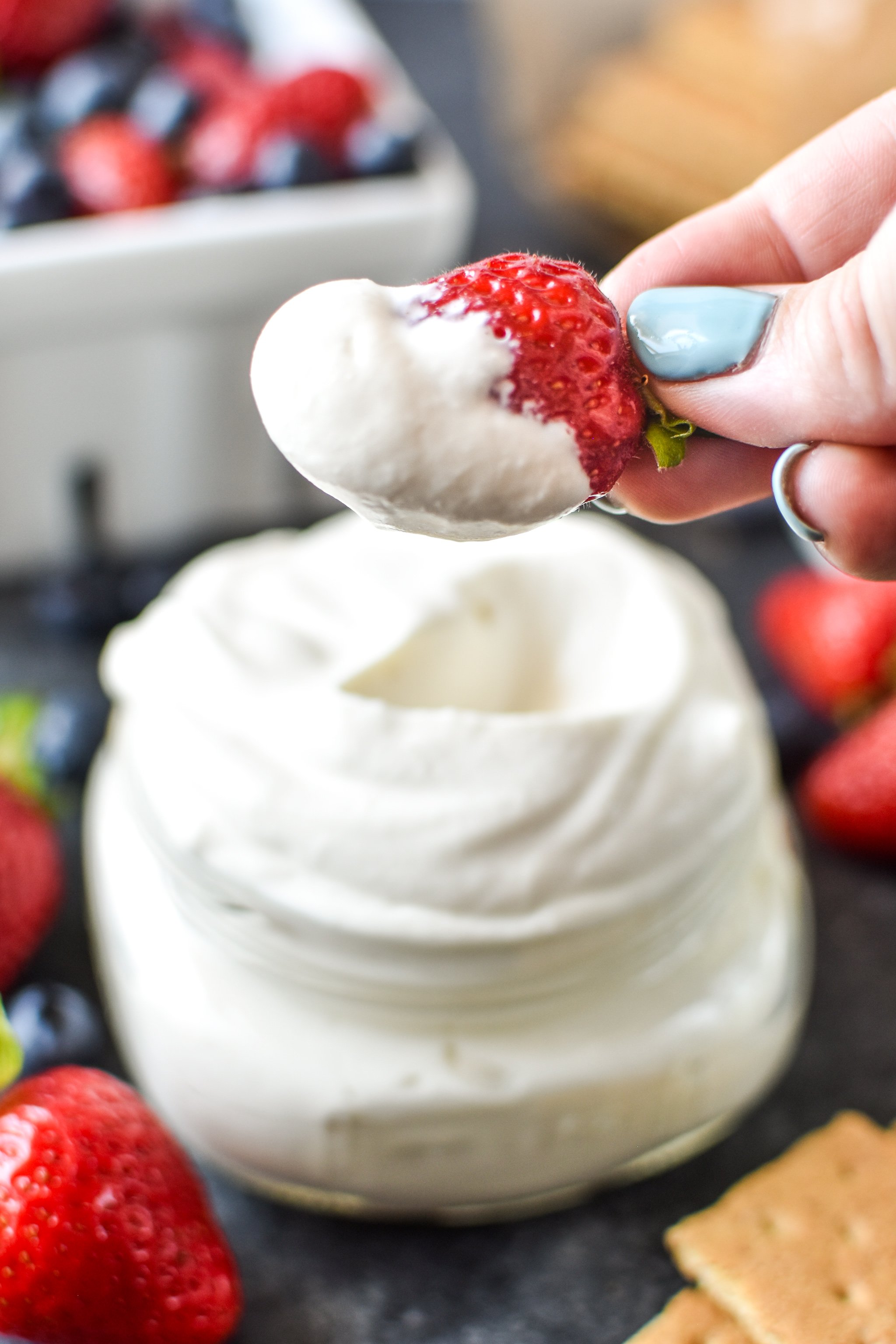 Dipping a strawberry in the whipped greek yogurt.