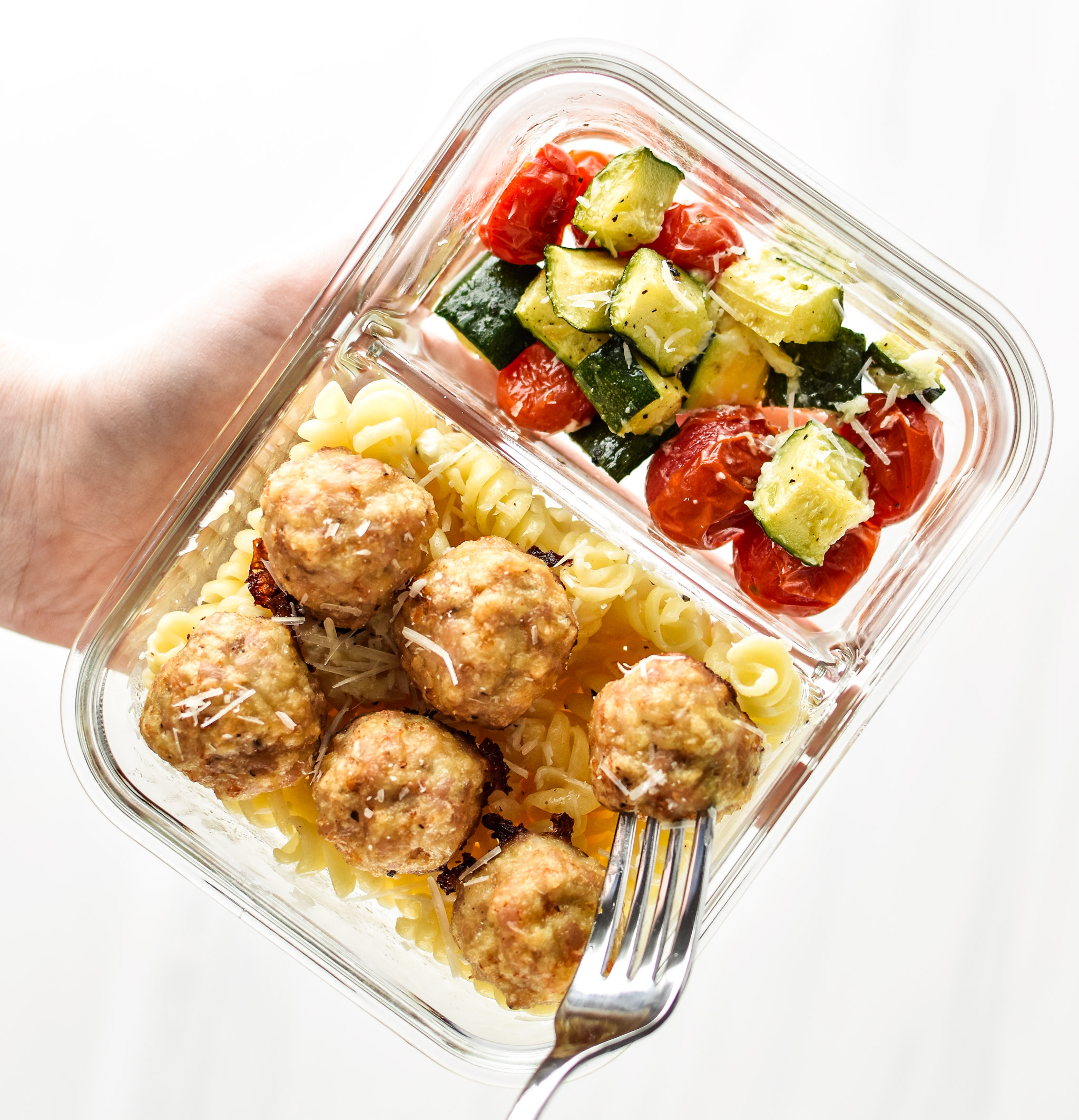 Holding a meal prep bowl from the chicken meatballs two ways meal prep lunches