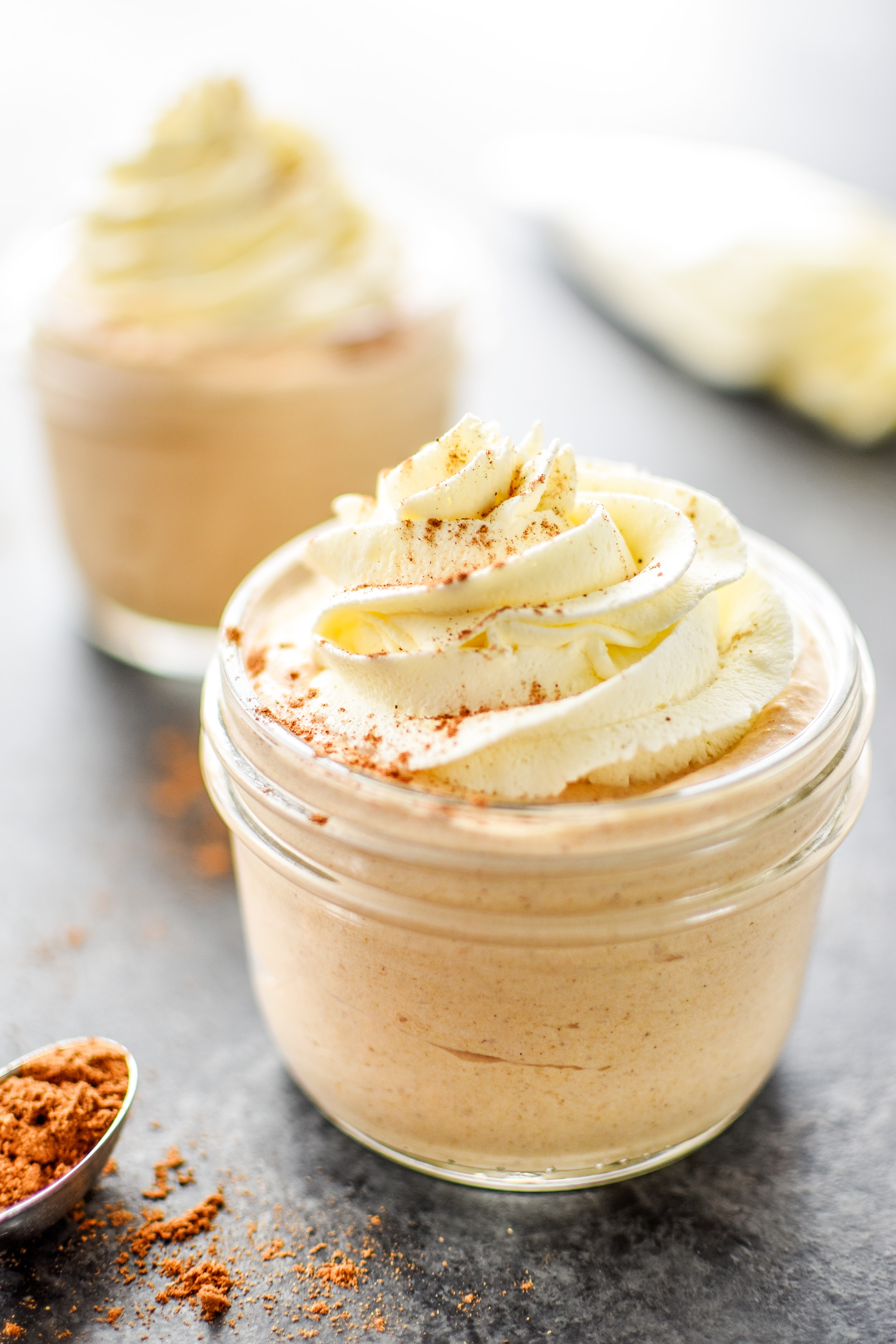 A jar of pumpkin whipped greek yogurt with whipped cream and pumpkin spice.