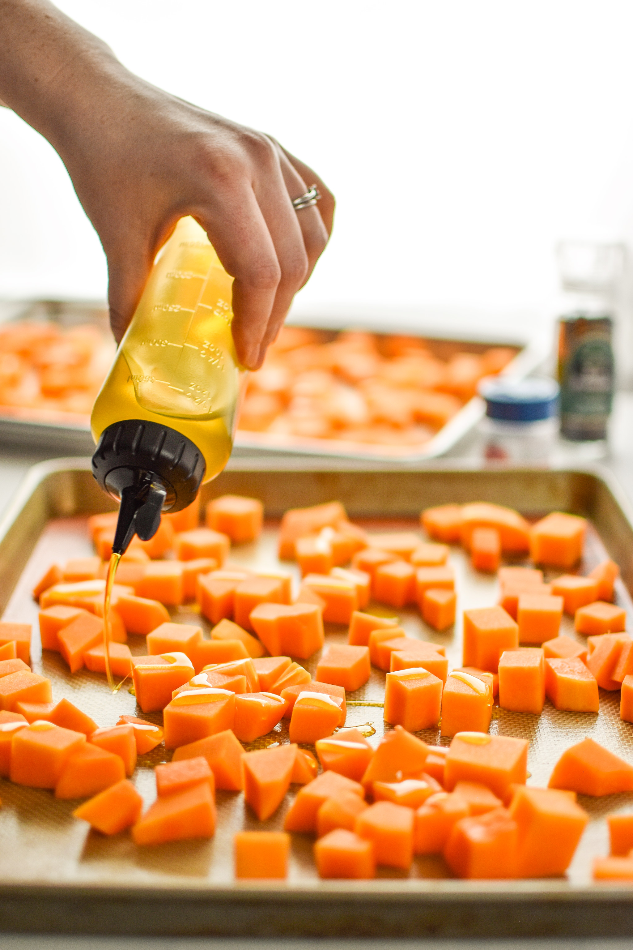 Using a chef squeeze bottle to add oil to the roasted butternut squash