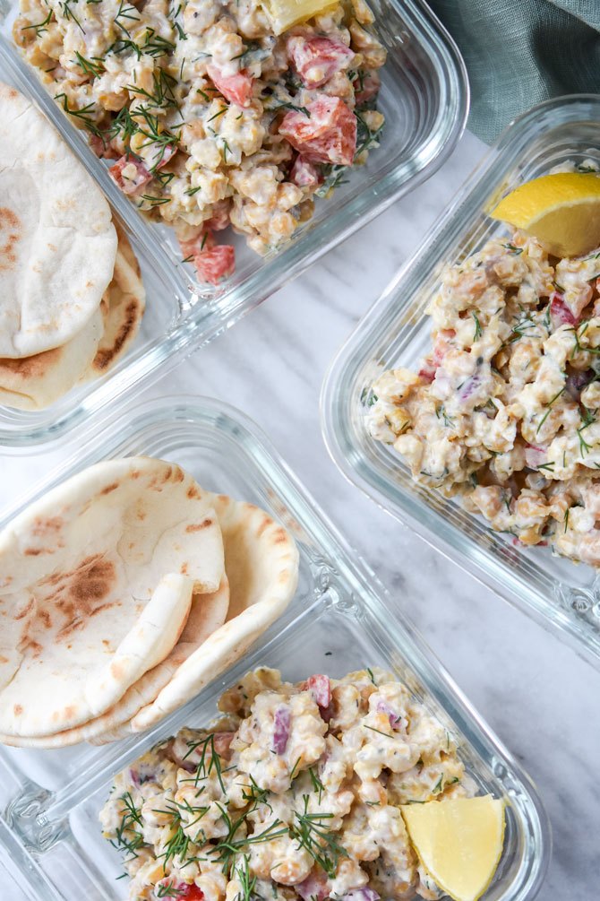Greek Chickpea salad with pita portioned into glass meal prep container for lunch. 