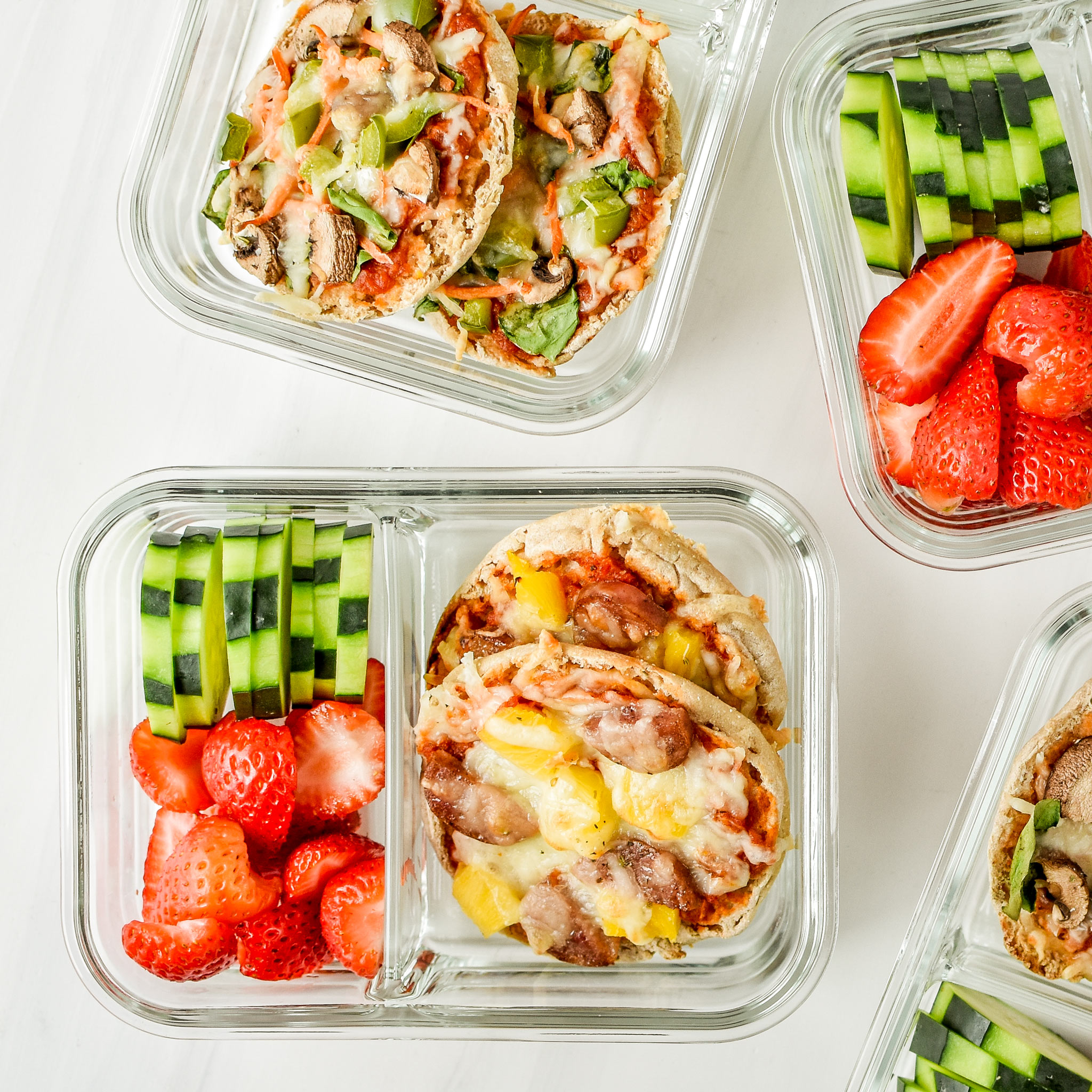 English muffin mini pizzas meal prep pictured from above in a meal prep container with fresh fruits and veggies.