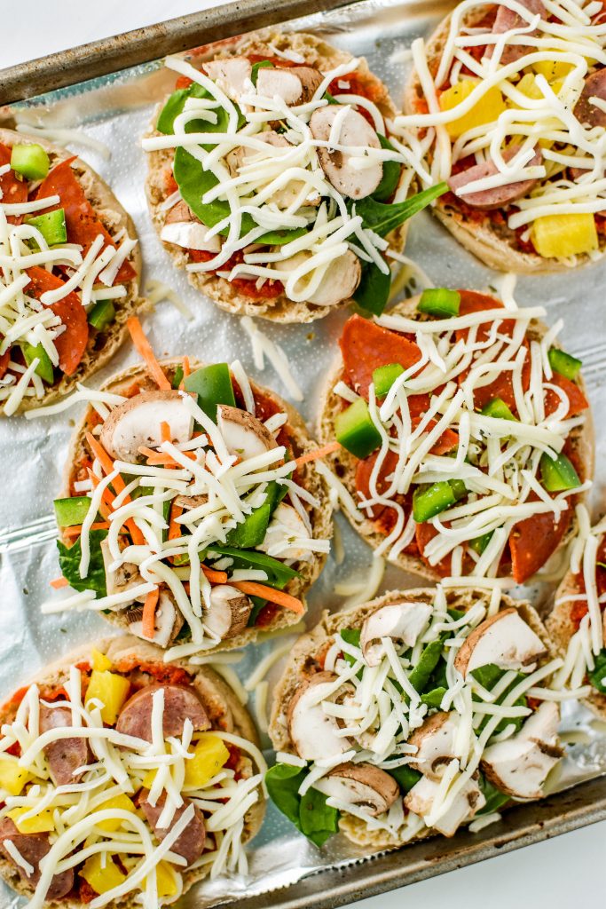 leftover ingredients on top of english muffins to make mini pizzas - a good example of ways to reduce food waste with meal planning.