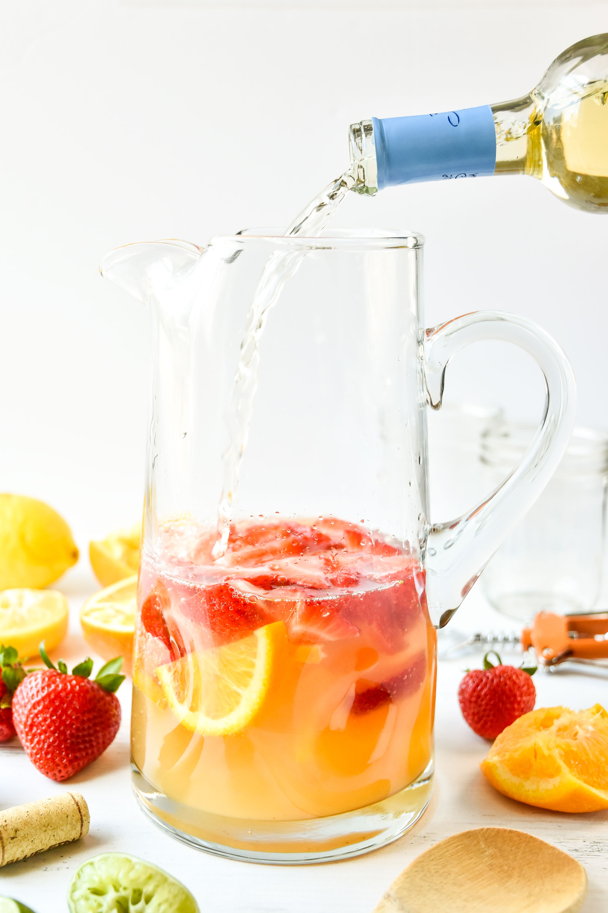 Pouring wine into pitcher of summer white wine sangria