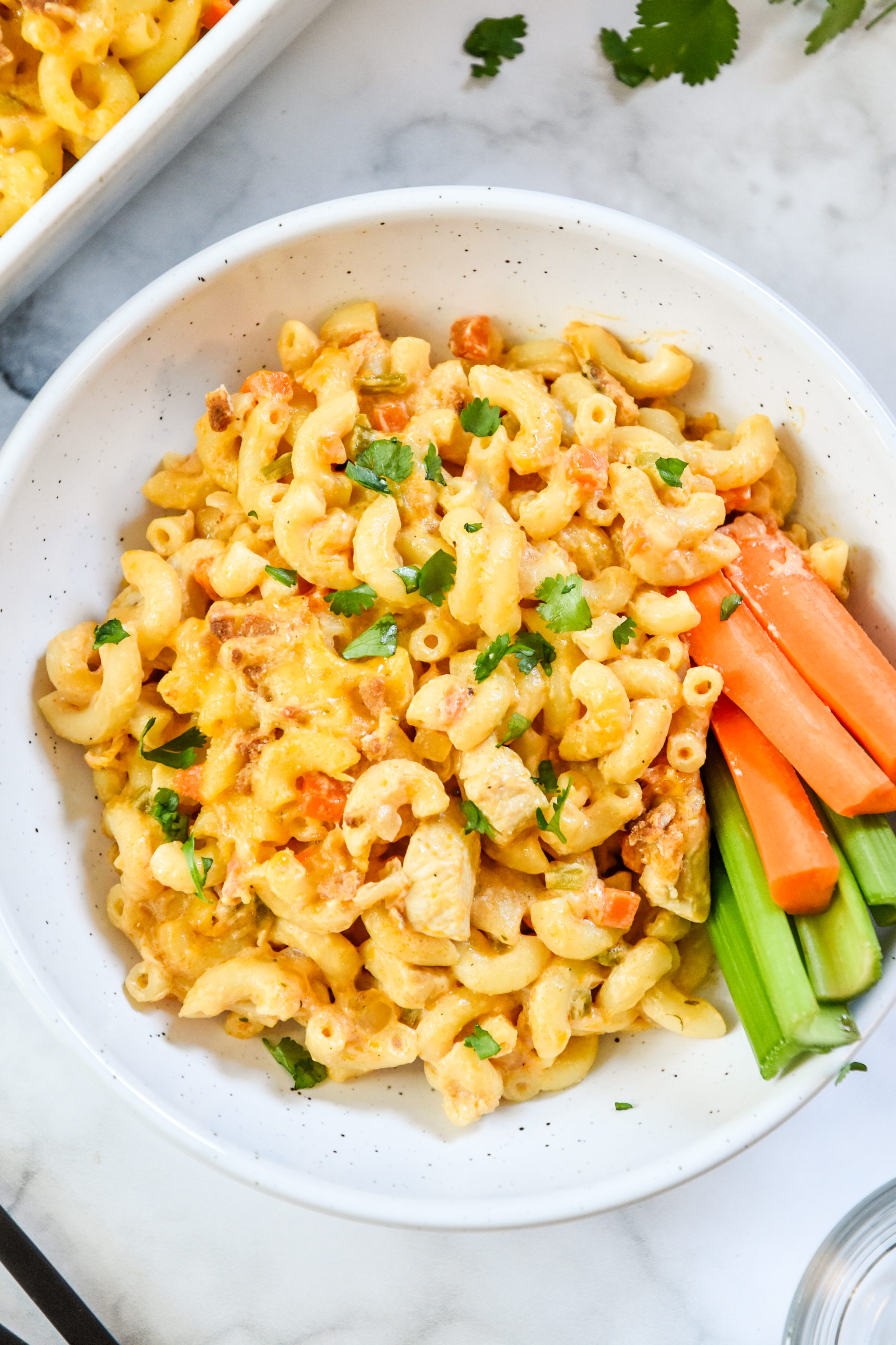 buffalo chicken mac and cheese in a bowl with carrots and celery