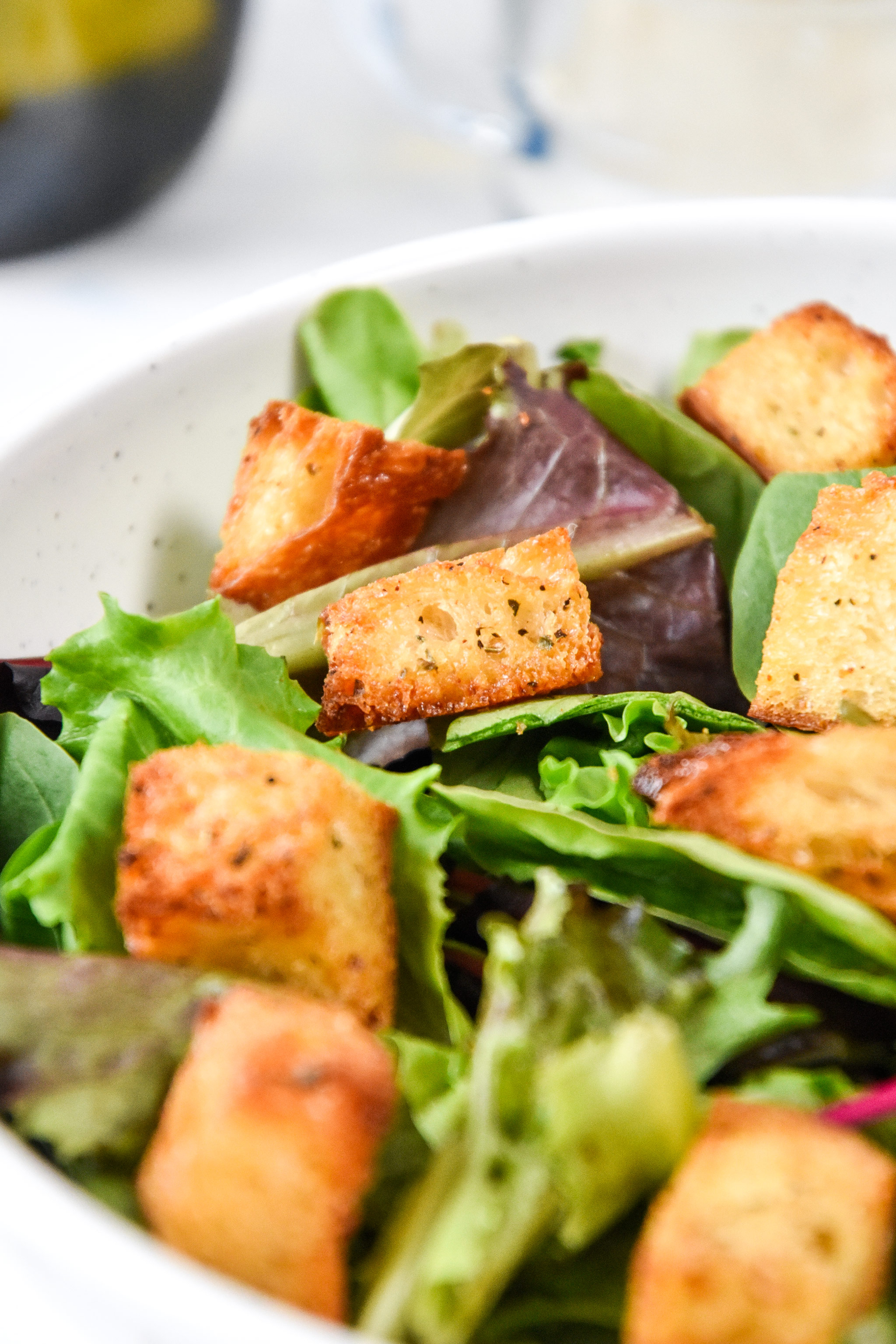 homemade croutons on a green salad in a bowl.