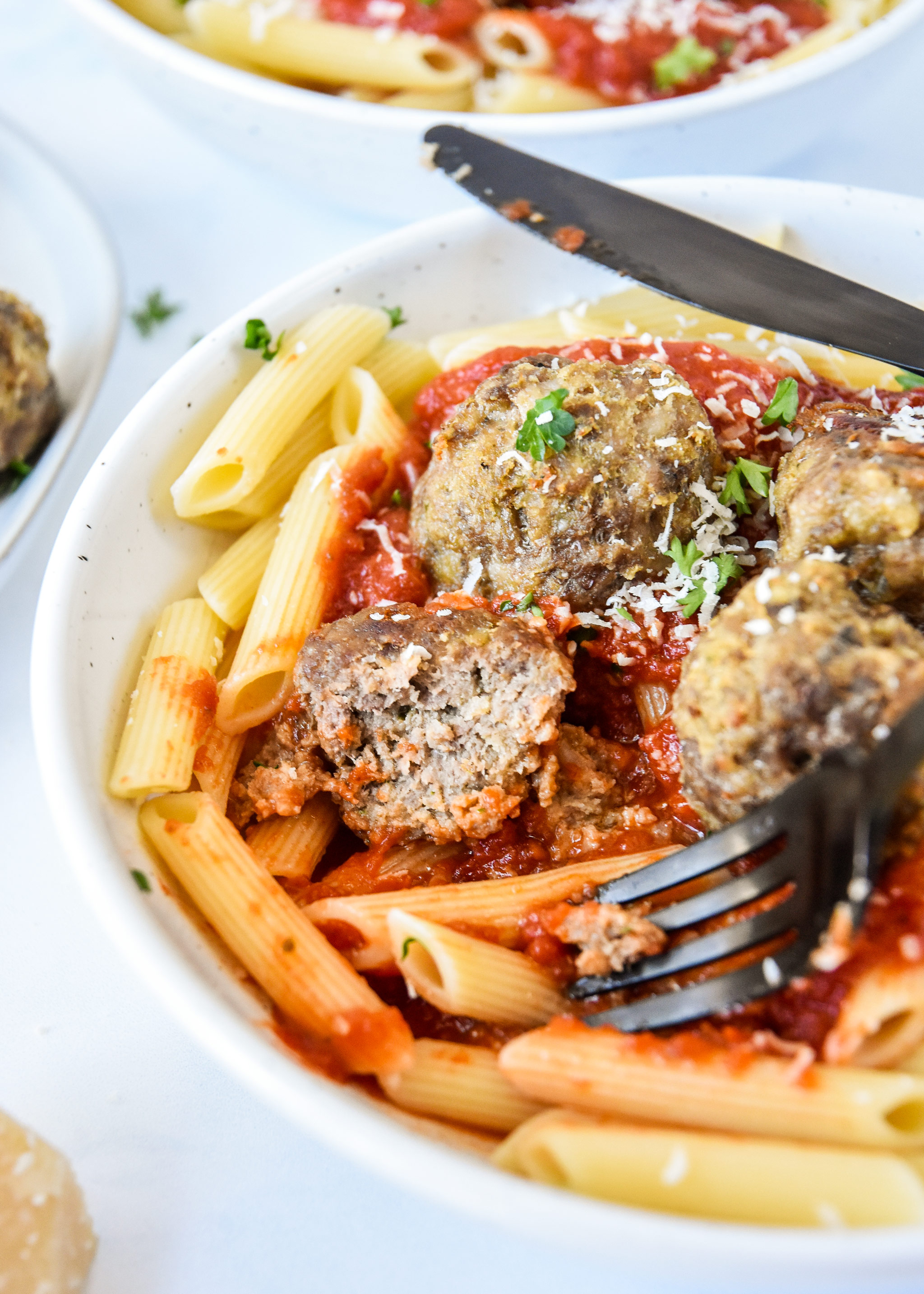 meatball cut in half with pasta and red sauce.