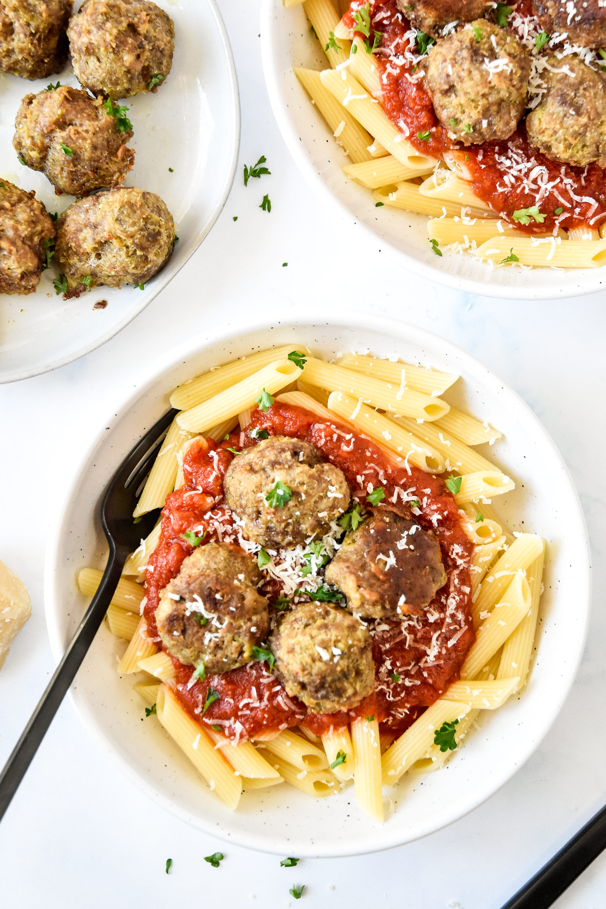 meatballs served with pasta and red sauce plus parmesan and parsley.