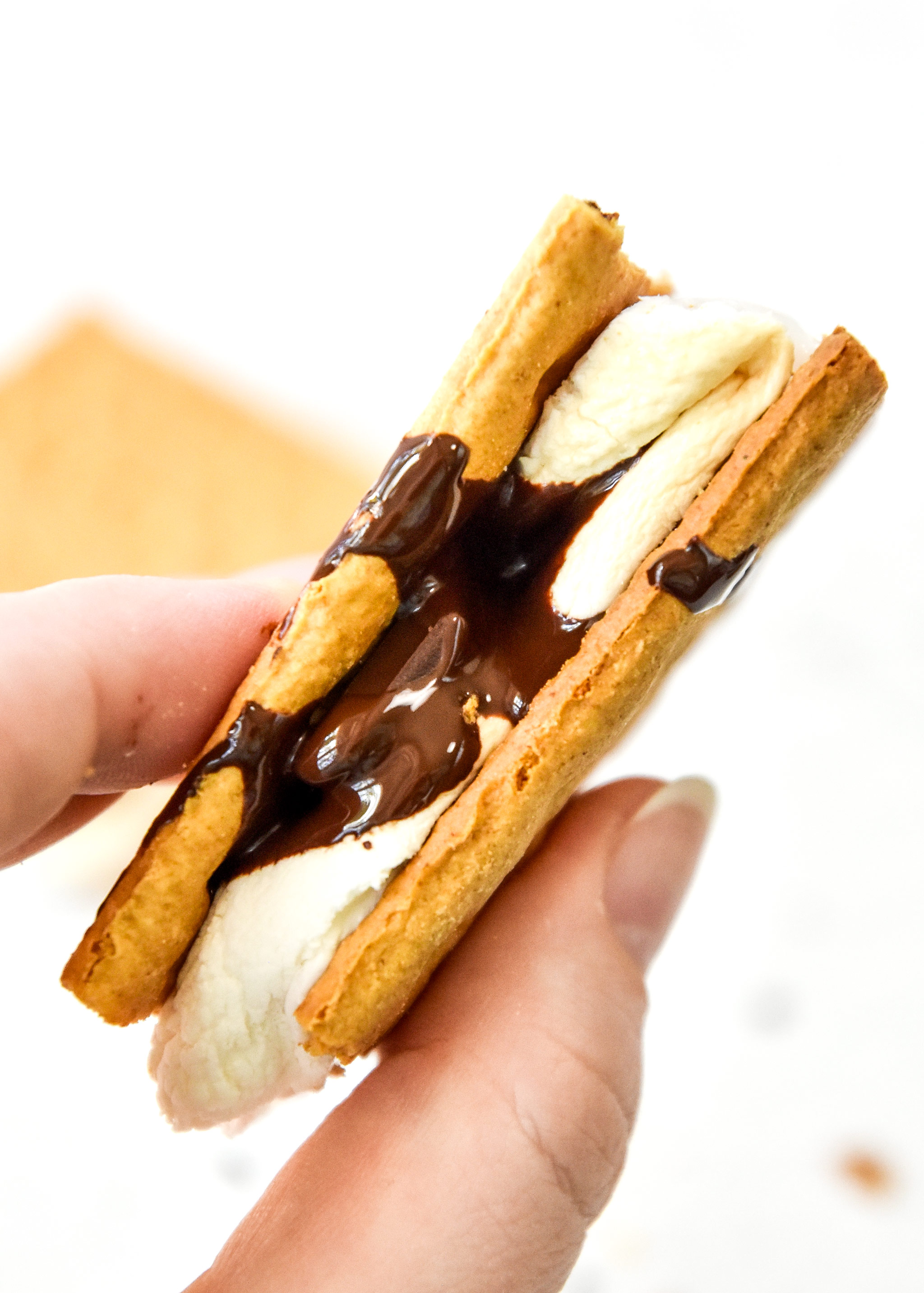 freshly made air fryer s'more with dripping chocolate in hand.