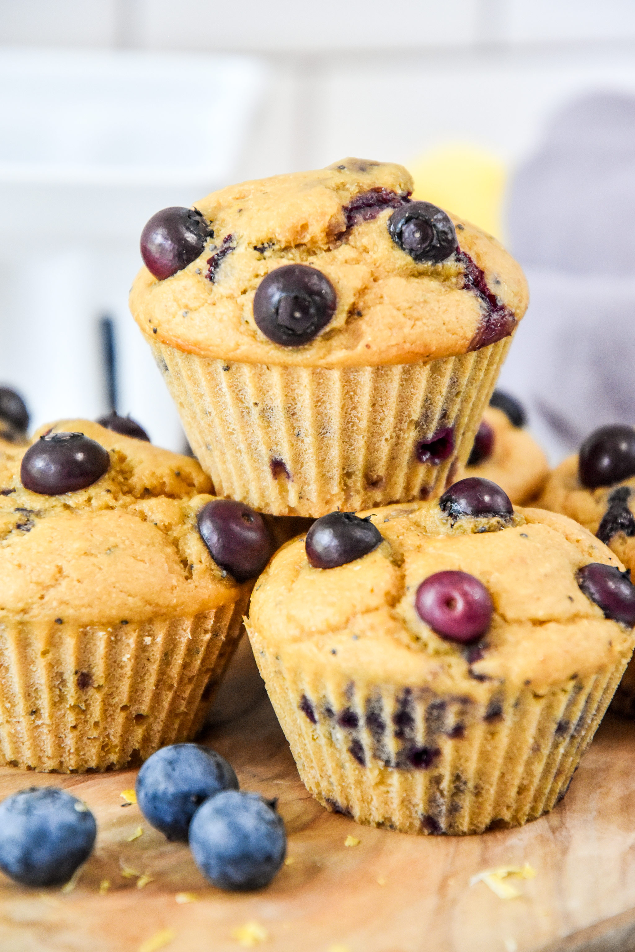muffins stacked on a cutting board with blueberries.