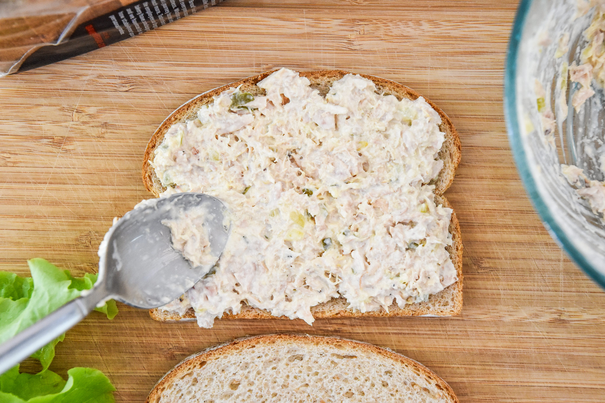spreading the tuna salad on bread.