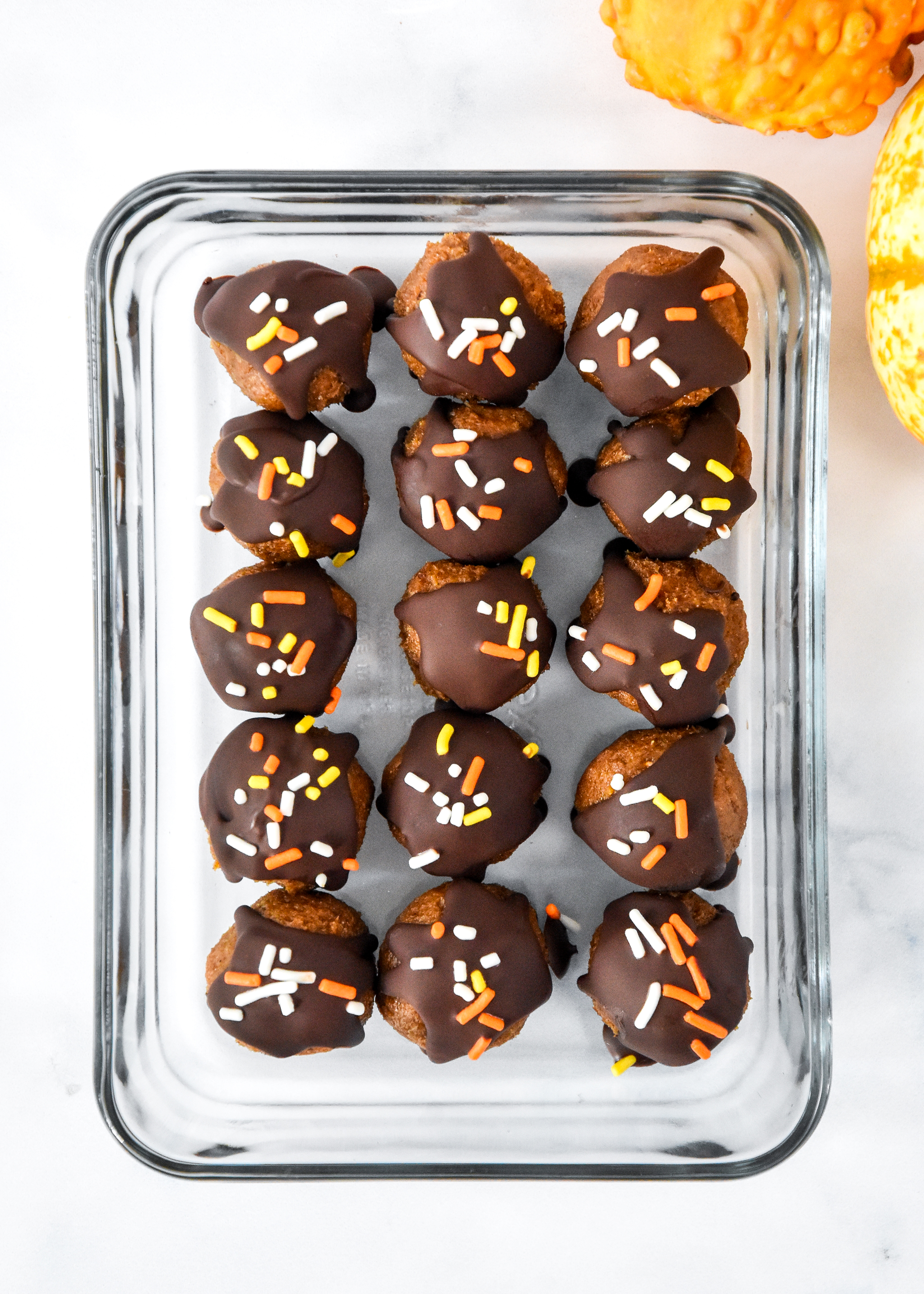 no-bake pumpkin spice date balls in a glass pyrex storage container.