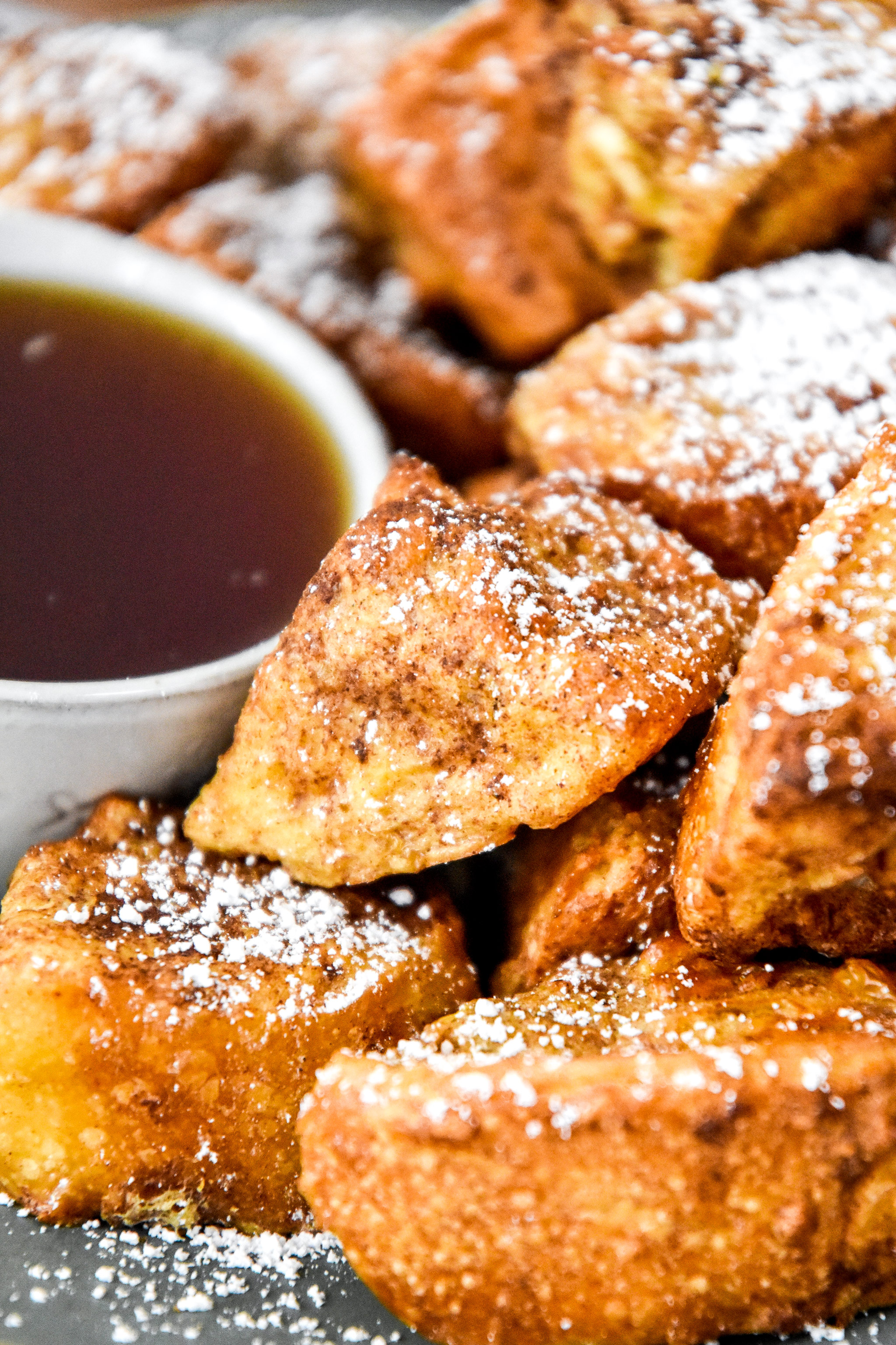 close up of air fryer french toast bites on a plate with powdered sugar.