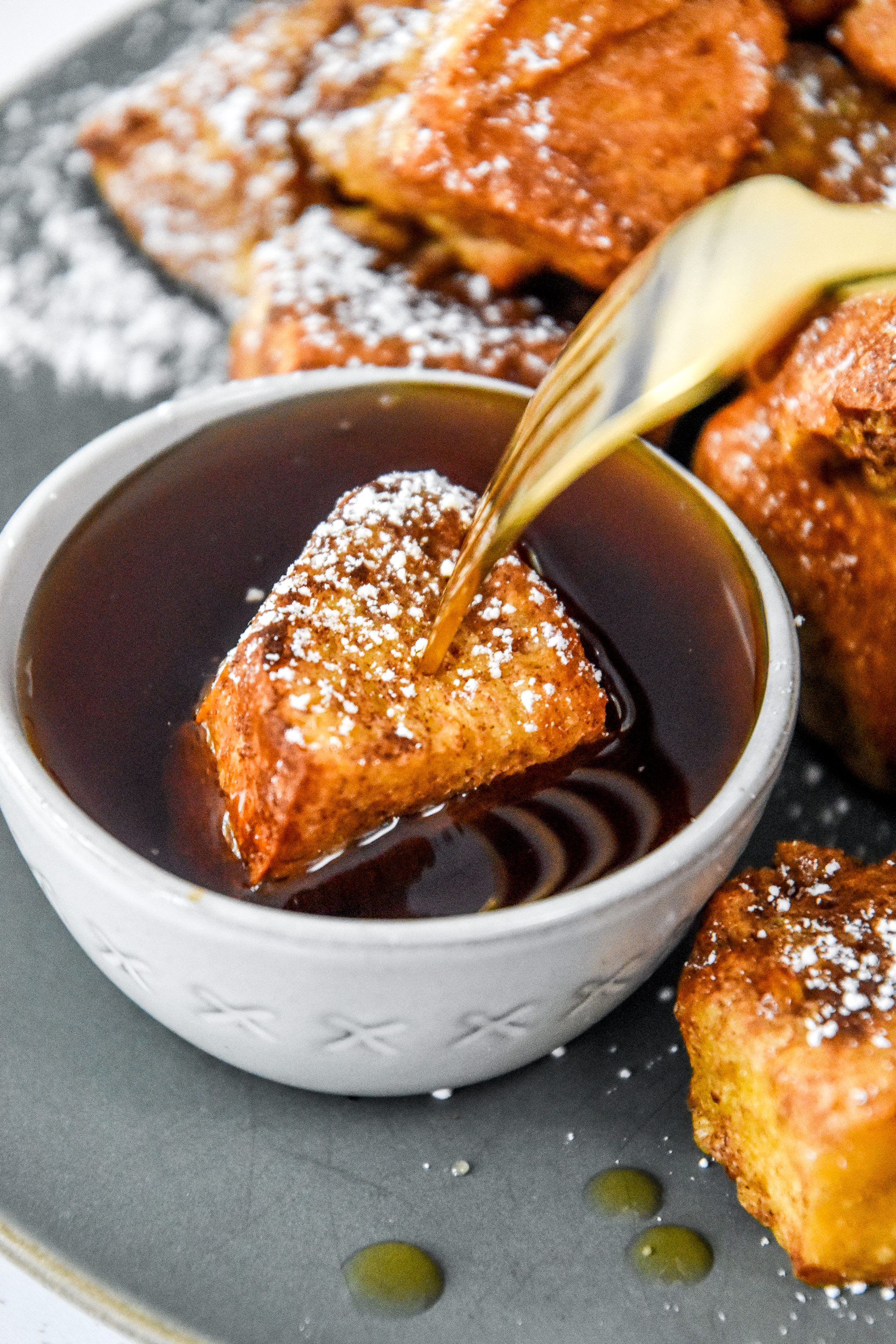 dipping a french toast bite into maple syrup.