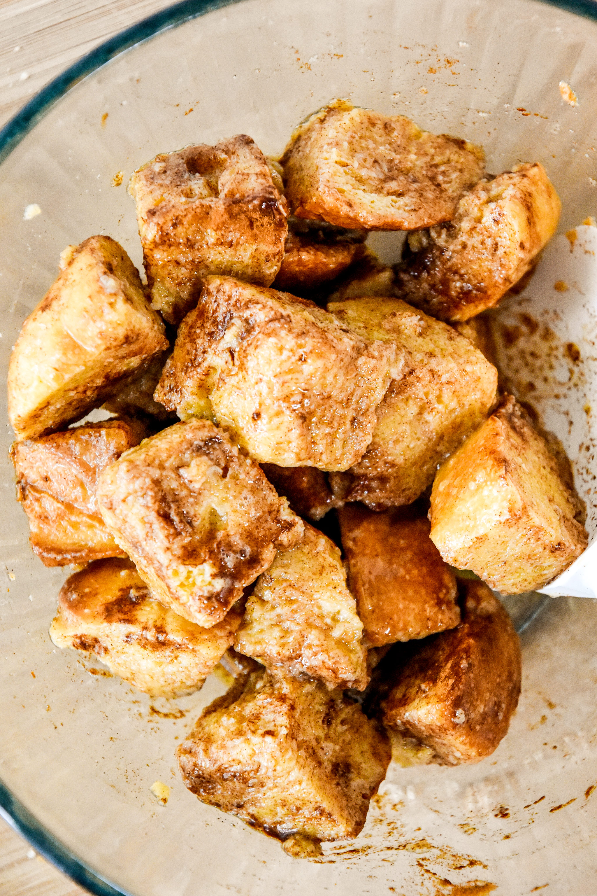 bread cubes soaked in egg mixture and cinnamon in a glass bowl.