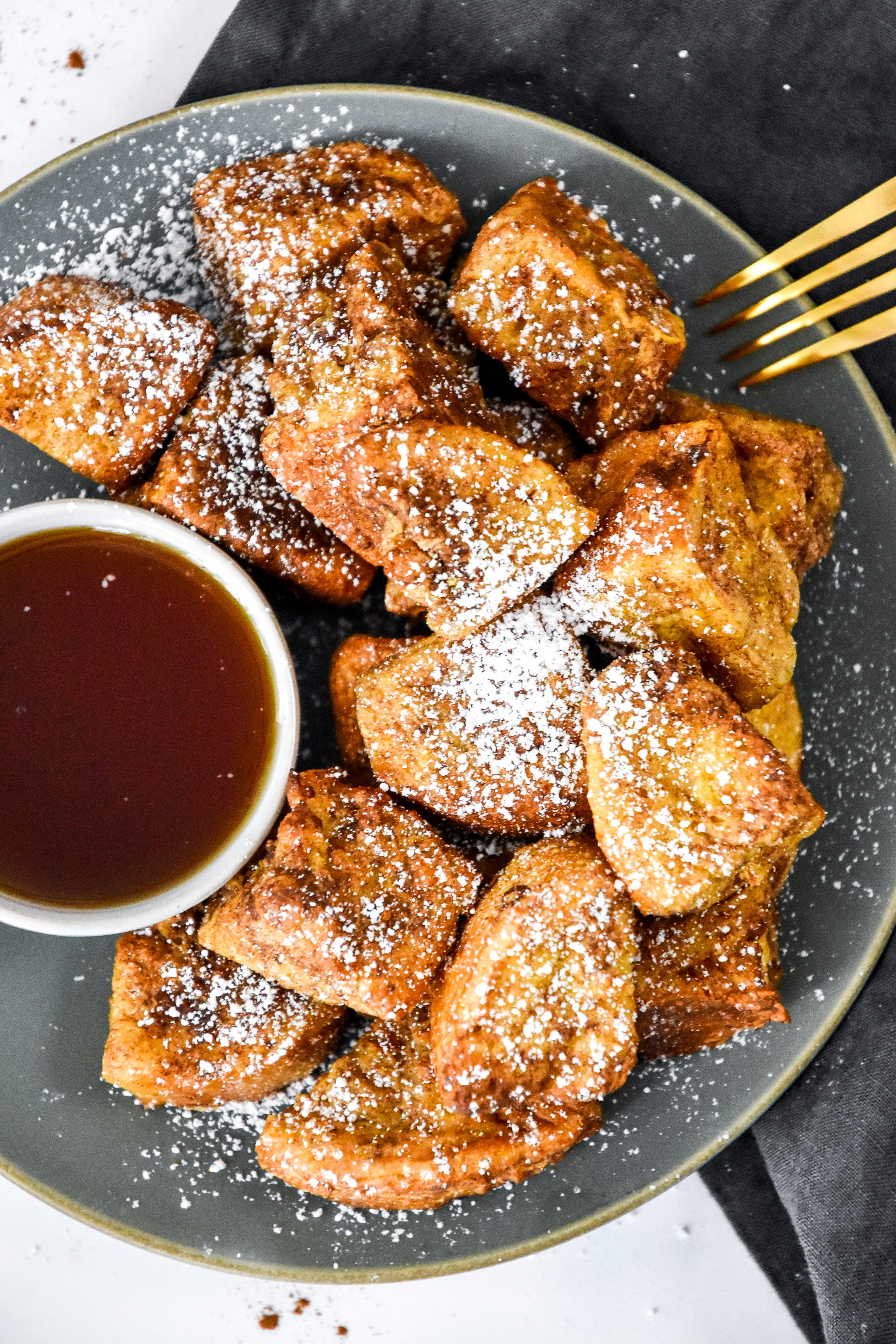 air fryer french toast bites on a plate with cup of syrup.