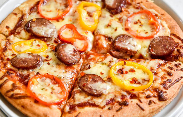 sausage and pepper personal pizzas cut into quarters on a plate