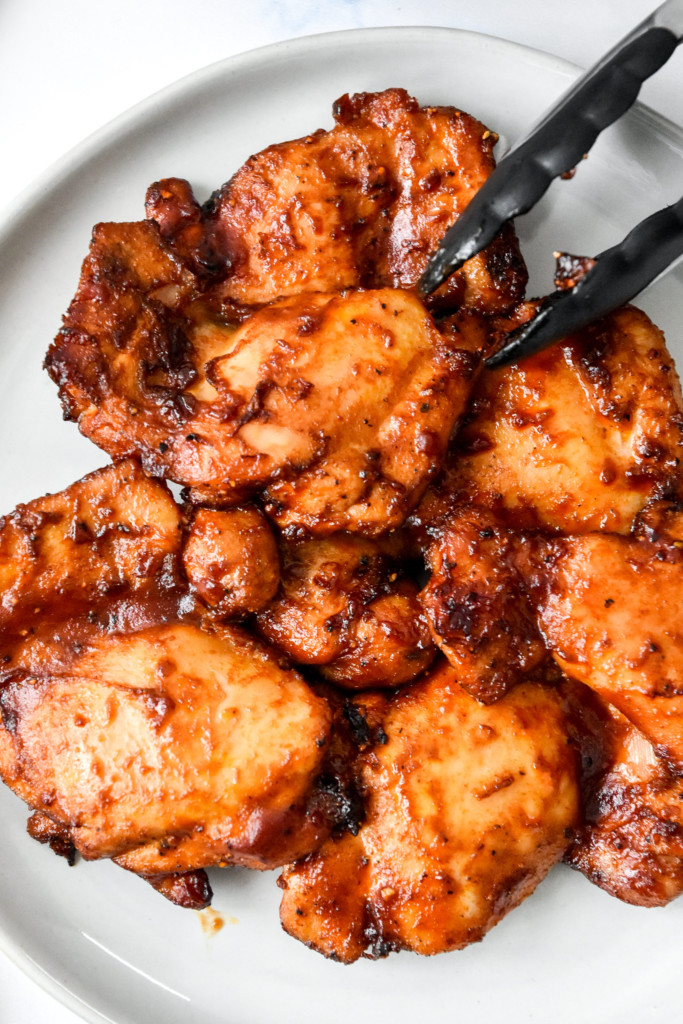cooked saucy air fryer boneless bbq chicken thighs on a plate.
