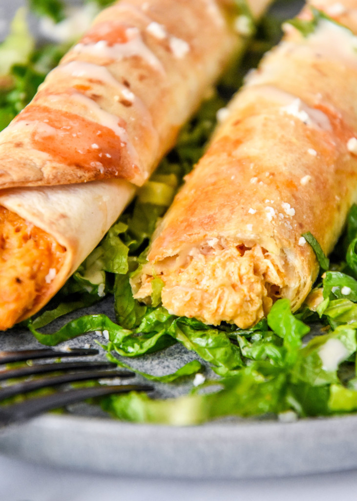 air fryer buffalo chicken flautas with a bite cut so you can see the inside.