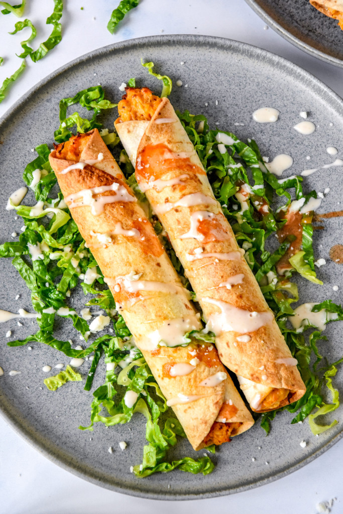 plated air fryer buffalo chicken flautas on a bed of shredded lettuce.