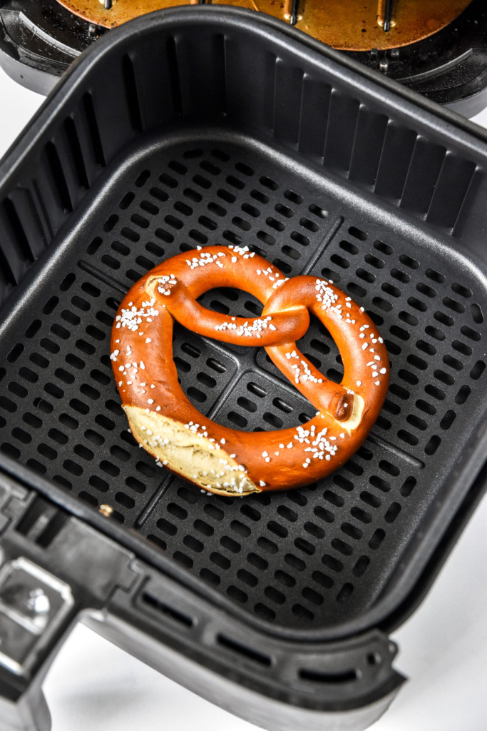 cooked pretzel with salt in the air fryer basket.