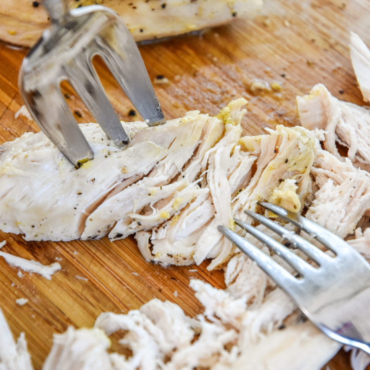 shredding chicken on a cutting board.