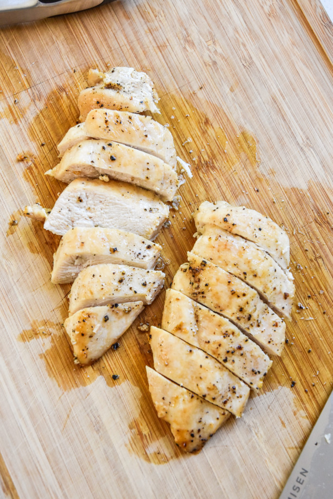 sliced chicken on a cutting board is one way how to cook chicken for meal prep.