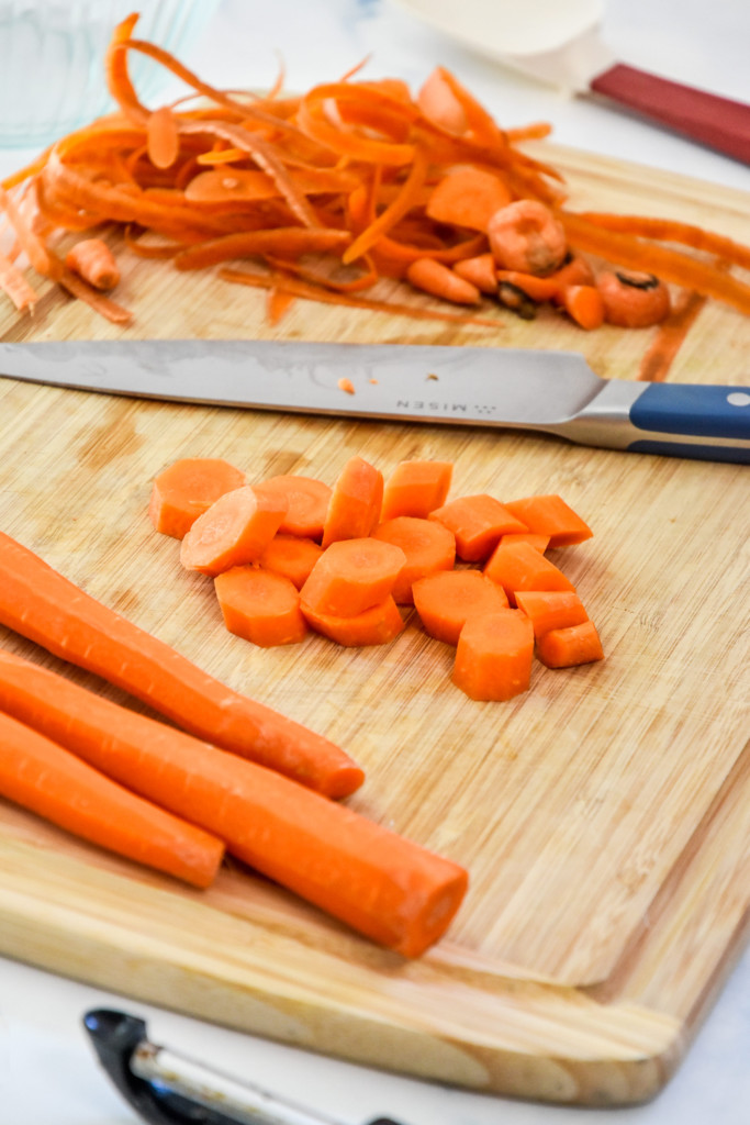 cutting and prepping carrots on a cutting board to make air fryer hot honey glazed carrots.