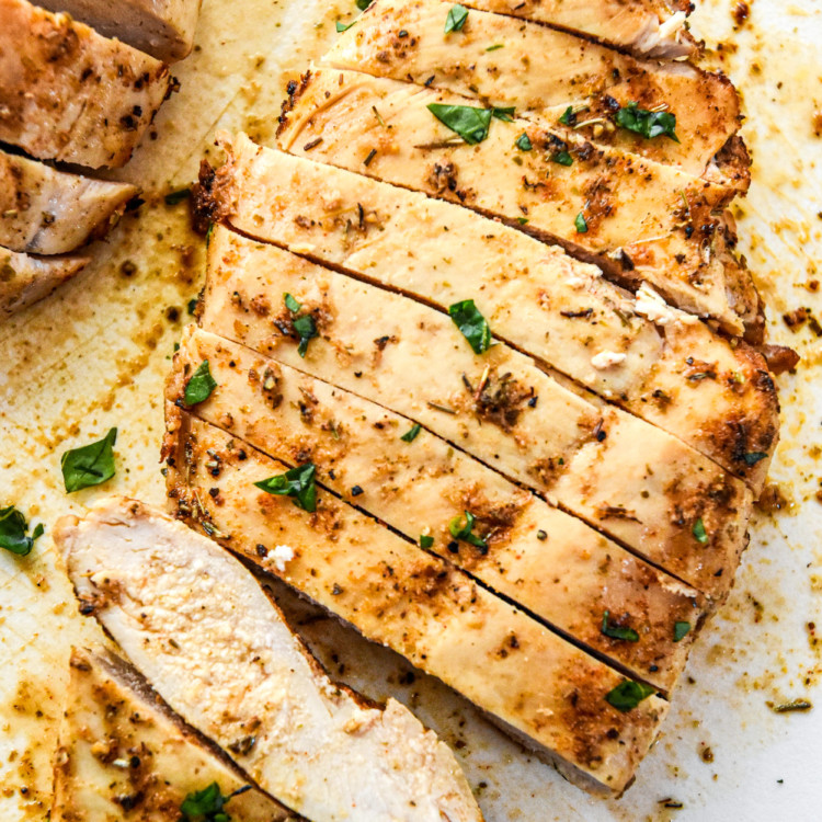 juicy air fryer chicken breasts cut into slices on a cutting board.