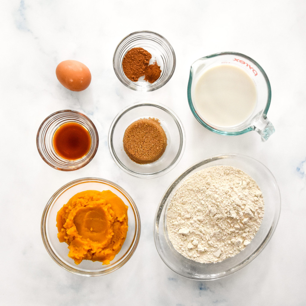 ingredients in glass bowls on a counter to make the pumpkin spice pancake mix muffins.