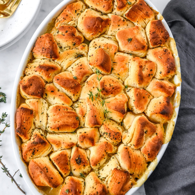 Chicken pot pie with biscuit crush in a white oval serving dish.