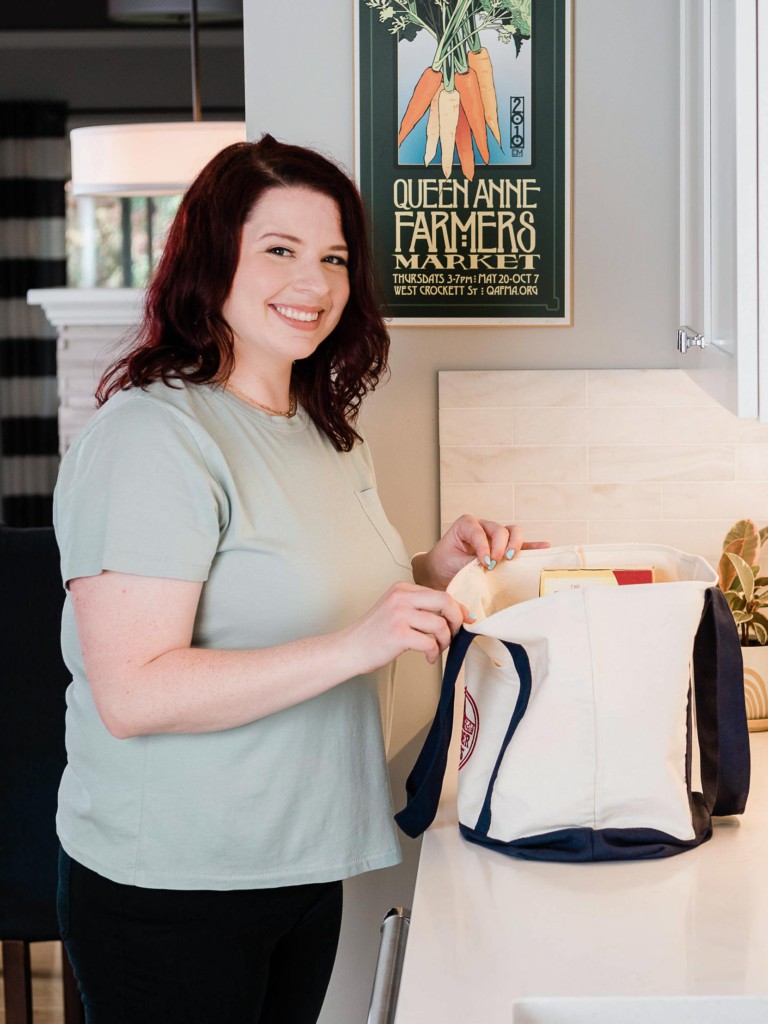 dark haired women in mint shirt smiling with grocery bag.