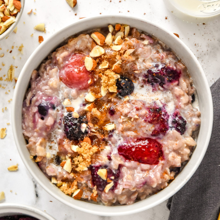 bowl of stovetop triple berry egg white oatmeal in a bowl with almonds on top.