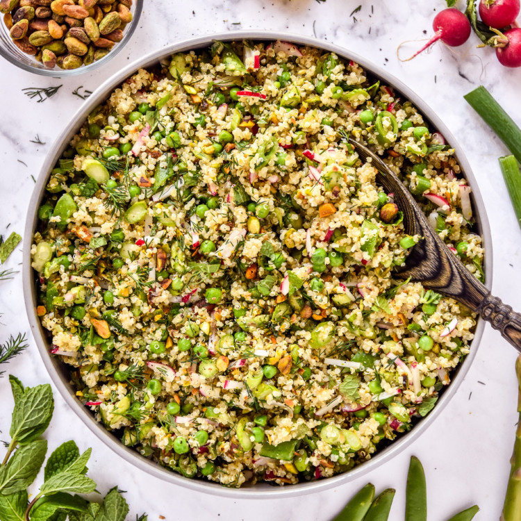 spring vegetable quinoa salad in a serving bowl with wooden spoon.