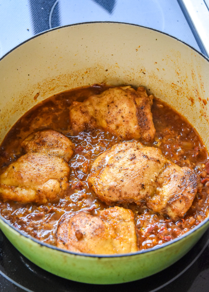 chicken thighs and tomato onion sauce simmering in a dutch oven.