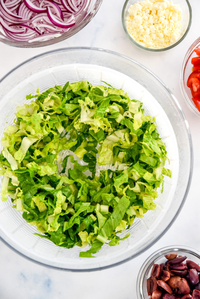 chopped romaine in a salad spinner for the greek chicken salad meal prep.
