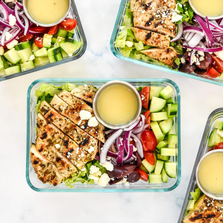 greek chicken salad meal prep bowls with dressing in glass container.
