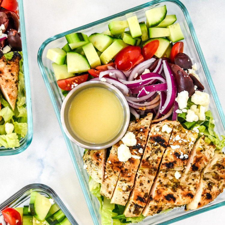 Greek chicken salad meal prep with dressing in a glass meal prep container.