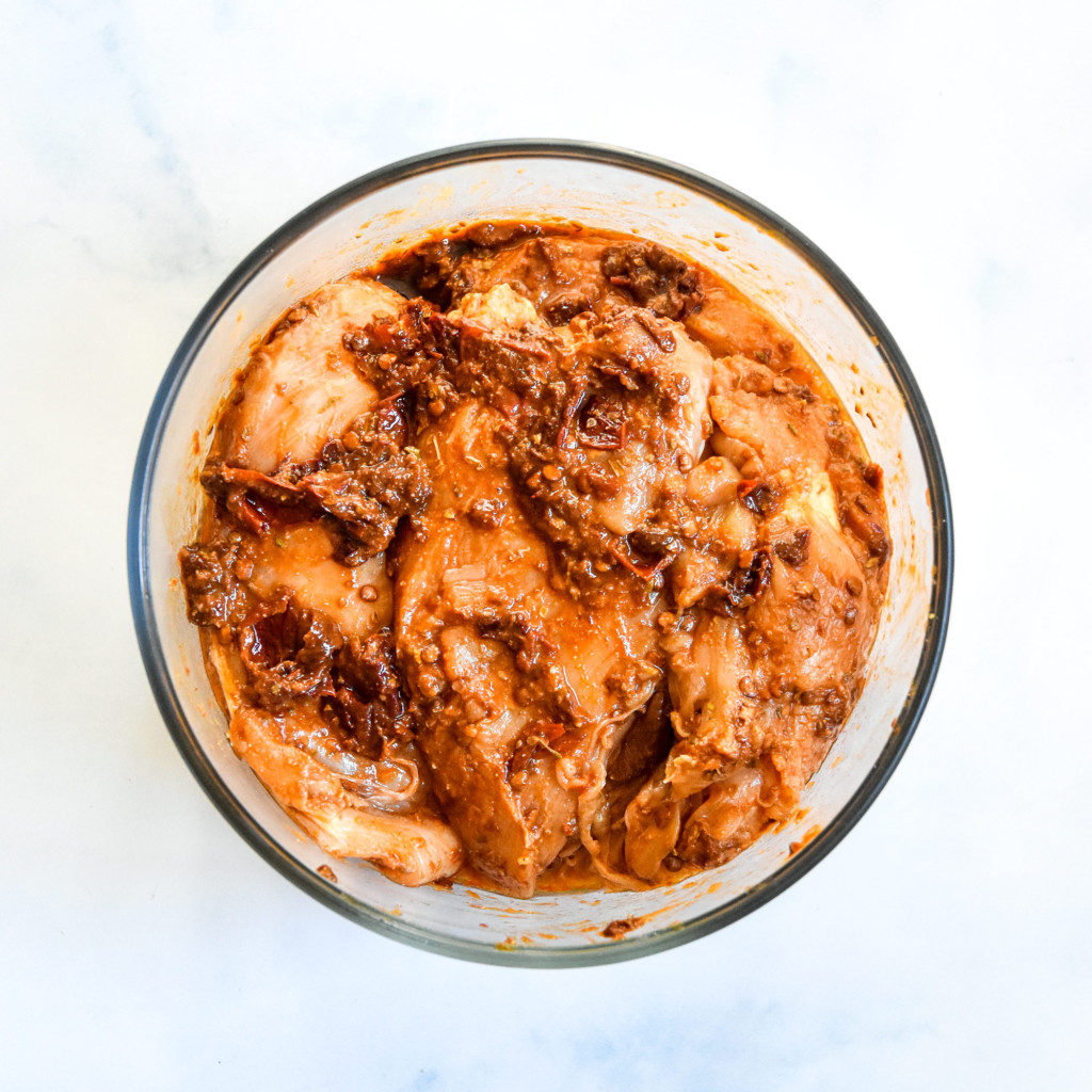 raw chipotle chicken marinating in a glass bowl.