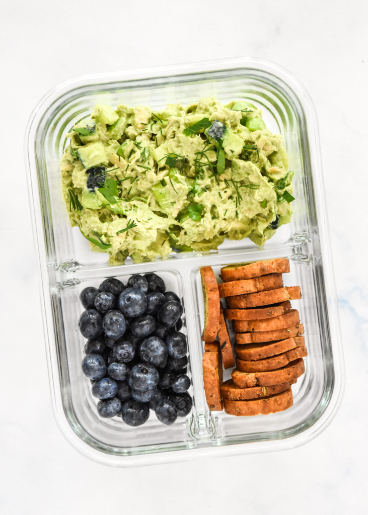green goddess tuna salad in a glass meal prep container with crackers and blueberries.