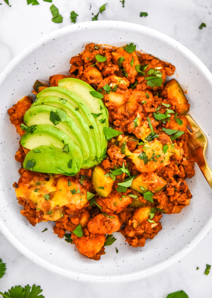 a bowl of one-pan soy chorizo gnocchi skillet with cilantro and avocado on top.